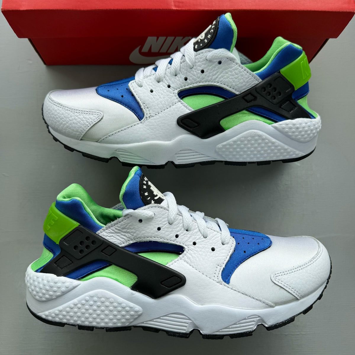 Nike Air Huarache white trainers with scream green and blue accents, mesh material.