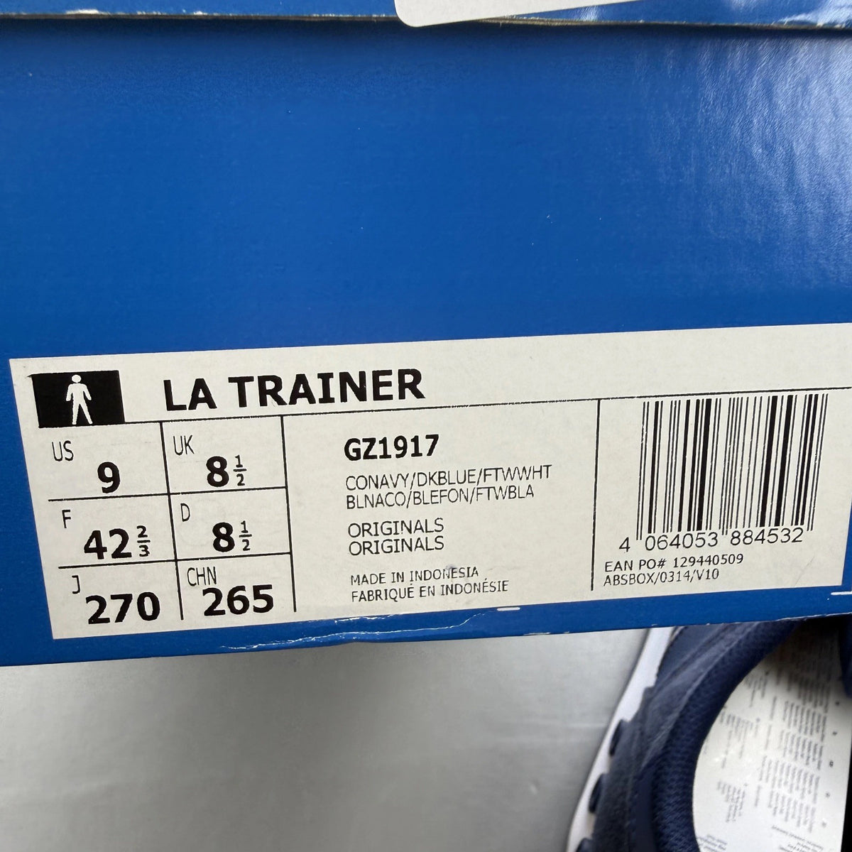 Adidas blue LA Trainer sneakers with white stripes and logo detailing.