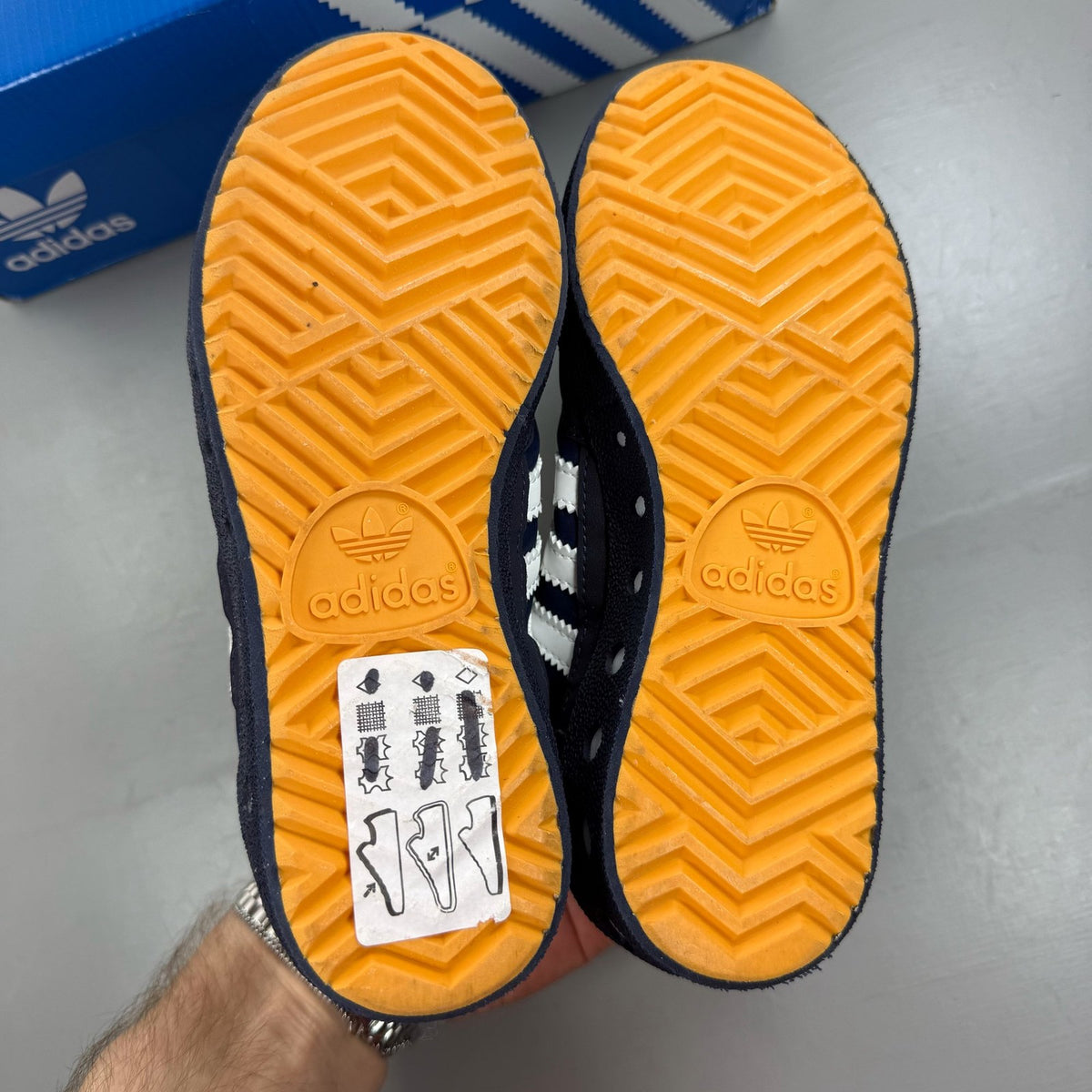 Adidas blue kids trainers with white and orange accents, featuring logo detail.