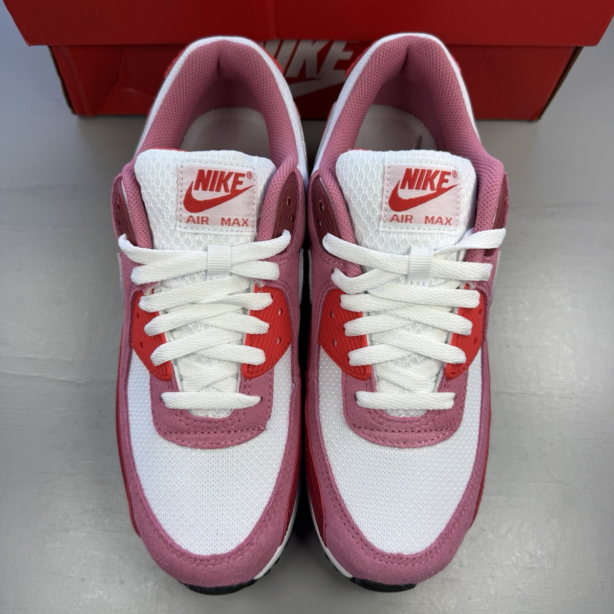 Nike Air Max 90 red trainers with white accents and signature swoosh logo.