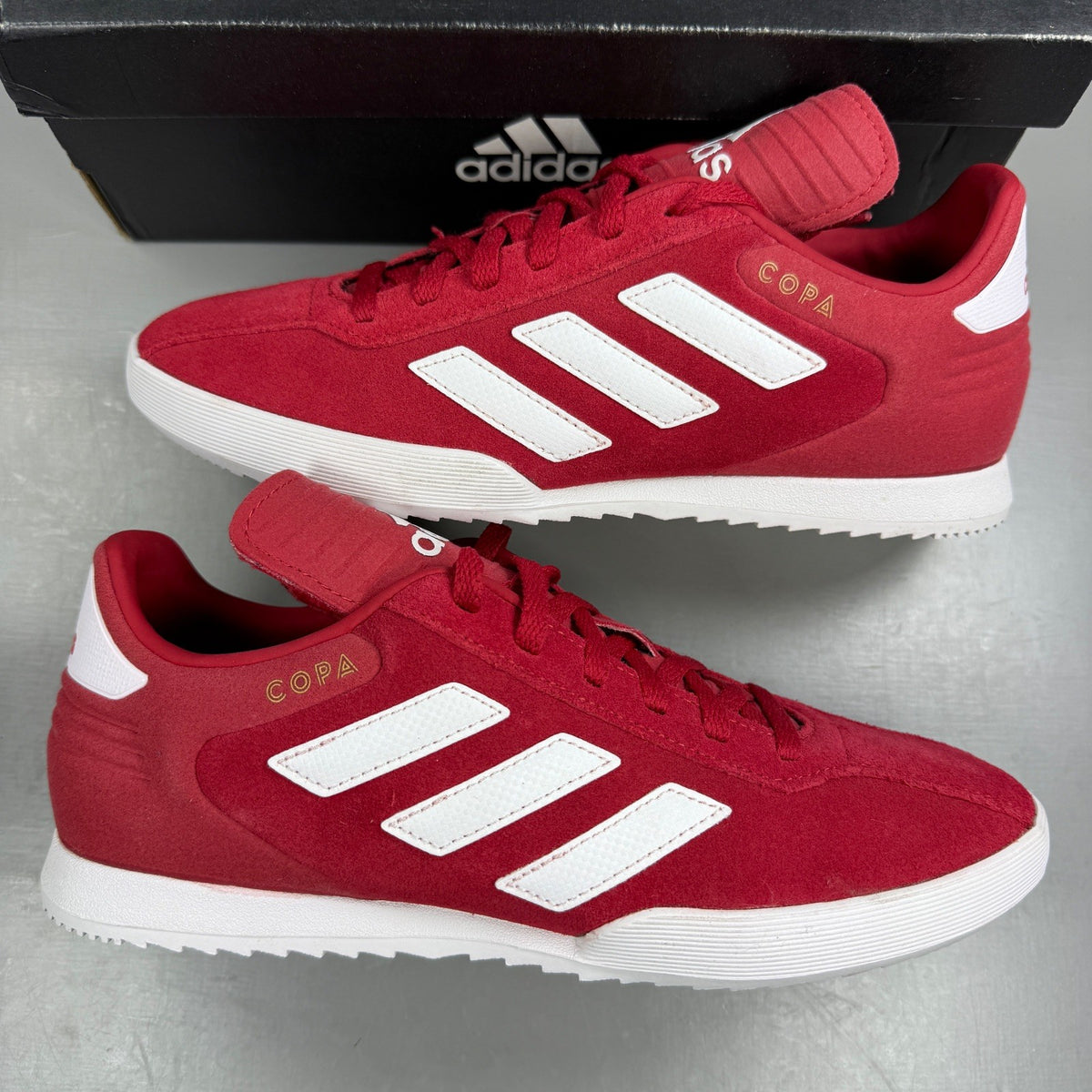 Adidas red suede running trainers with white logo and classic design details.