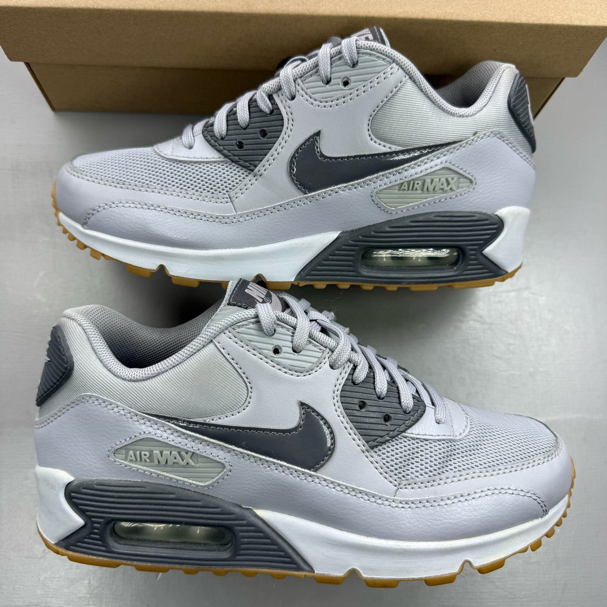 Nike Air Max 90 grey trainers with gum sole and iconic swoosh logo.