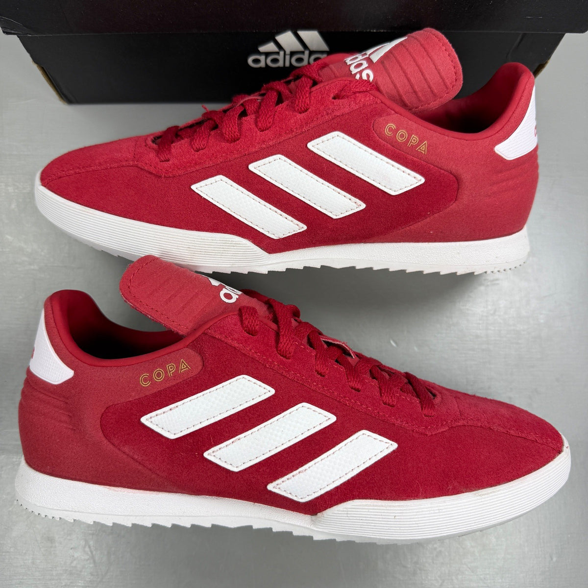 Adidas red suede running trainers with white logo and classic design details.