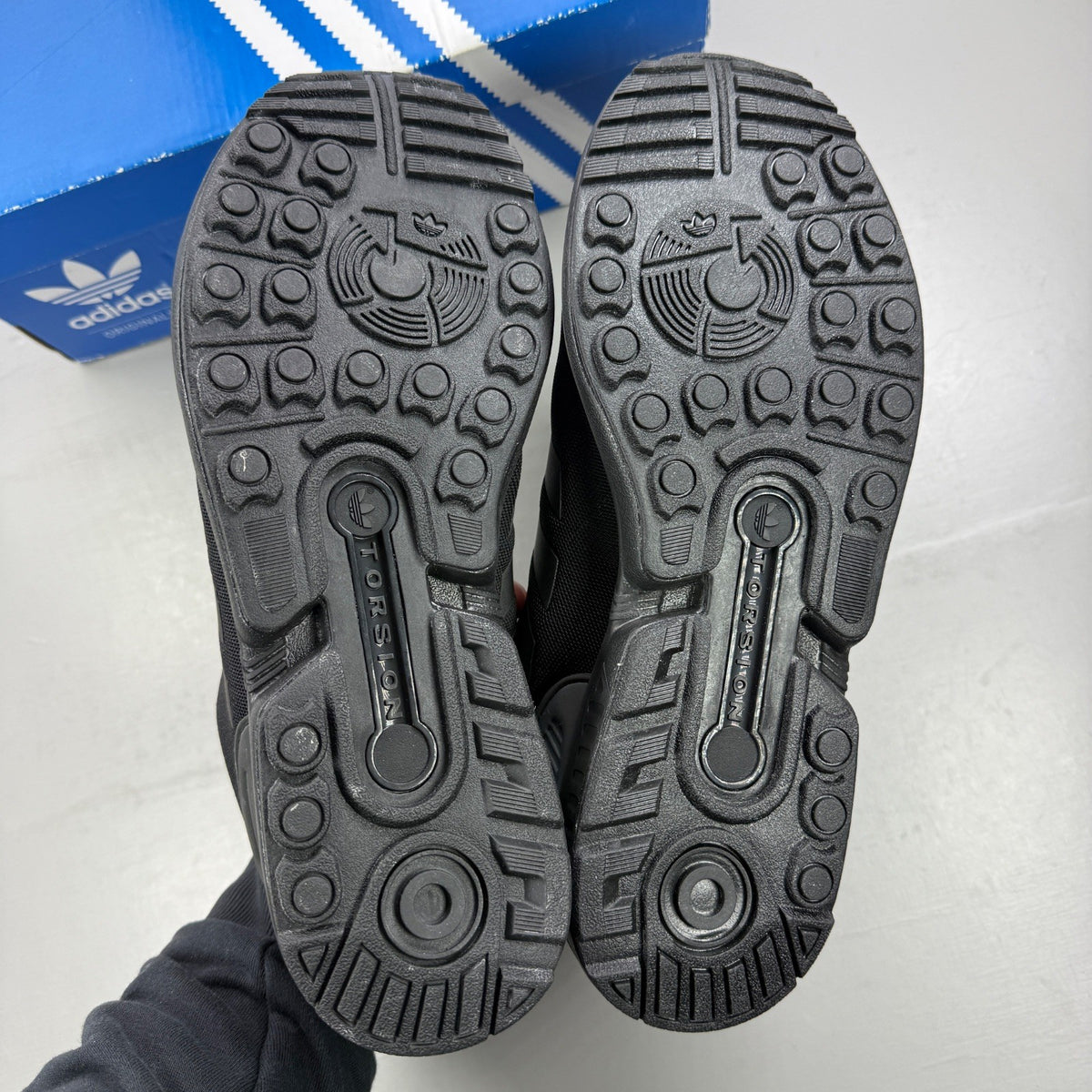 Adidas black trainers with iridescent accents and signature logo on tongue.