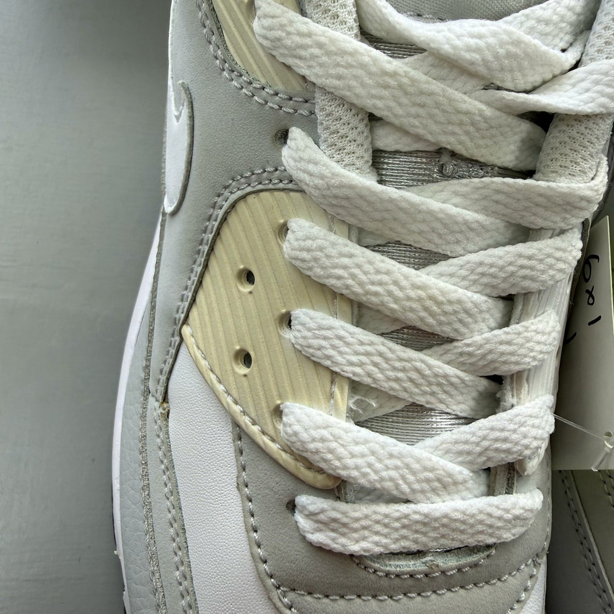 Nike Air Max 90 white trainers with grey accents and logo detailing.