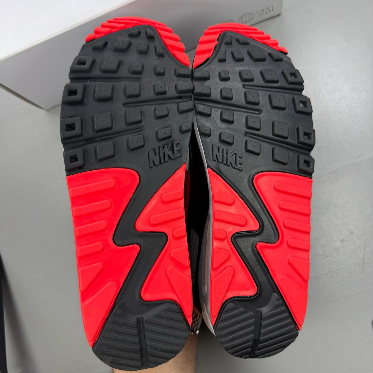 Nike Air Max 90 black trainers with radiant red and wolf grey accents, logo detail.