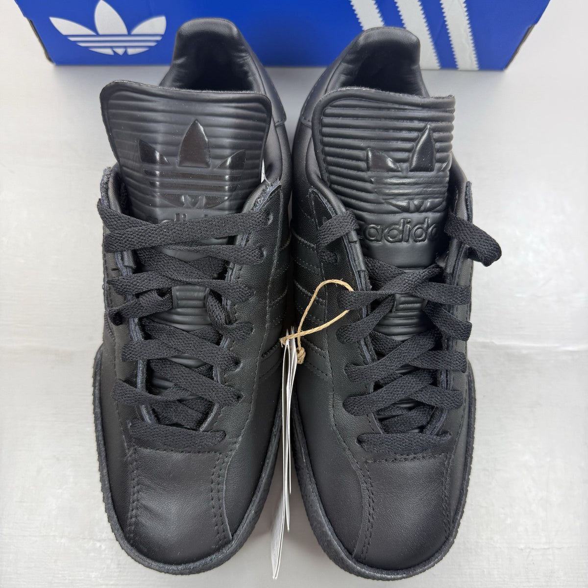 Adidas Samba Super black trainers with white and gold logo detailing.