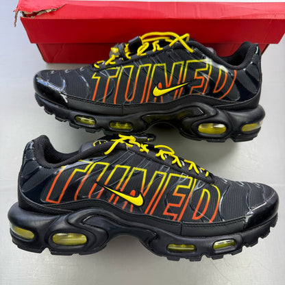 Nike Air Max Plus TN black trainers with signature logo and vibrant sunrise detailing.