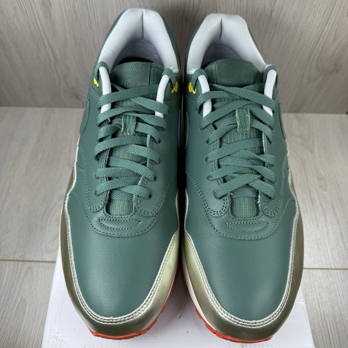 Nike Air Max 1 trainers green with white and silver accents, featuring iconic logo.