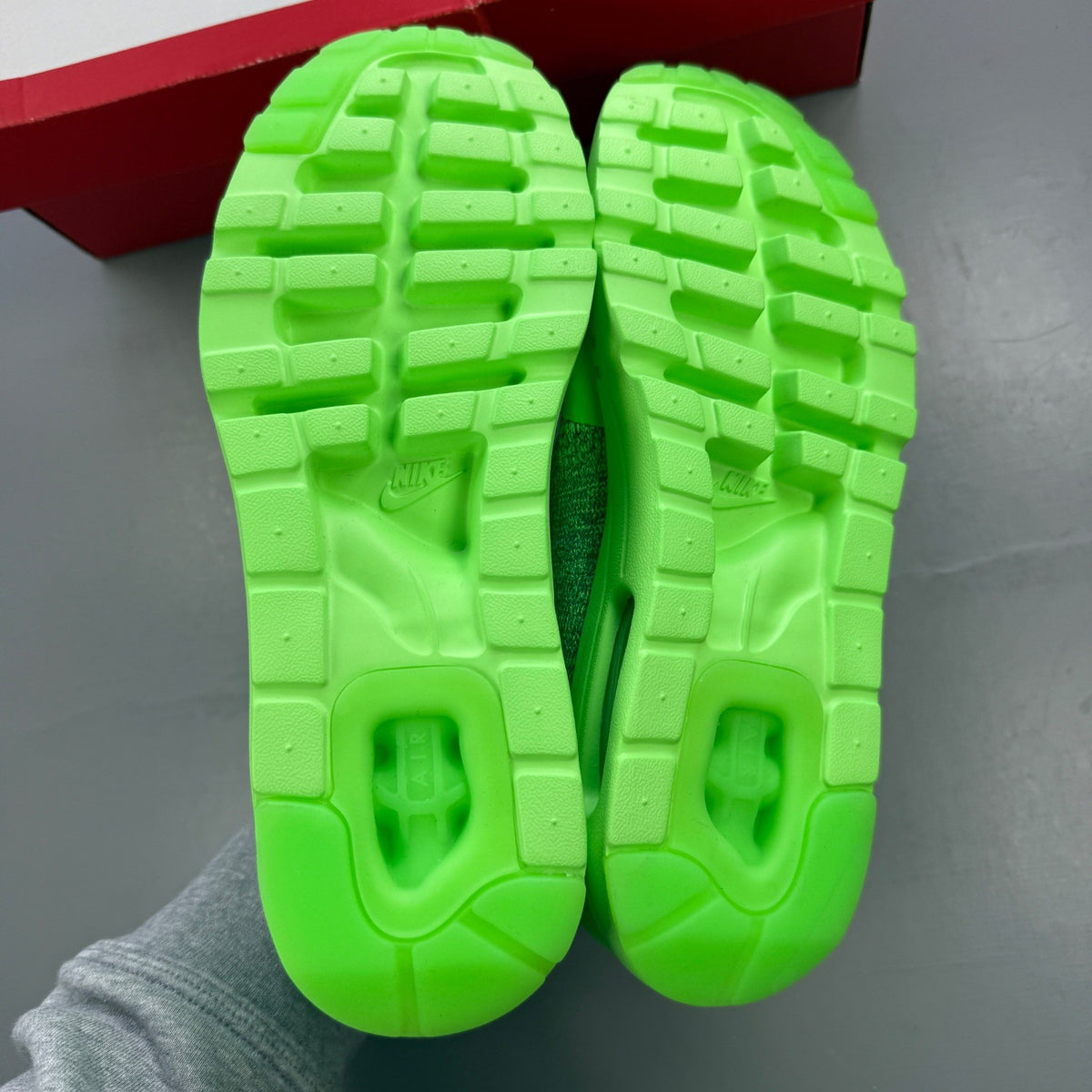 Nike trainers green Flyknit upper with Air Max cushioning and logo detail.