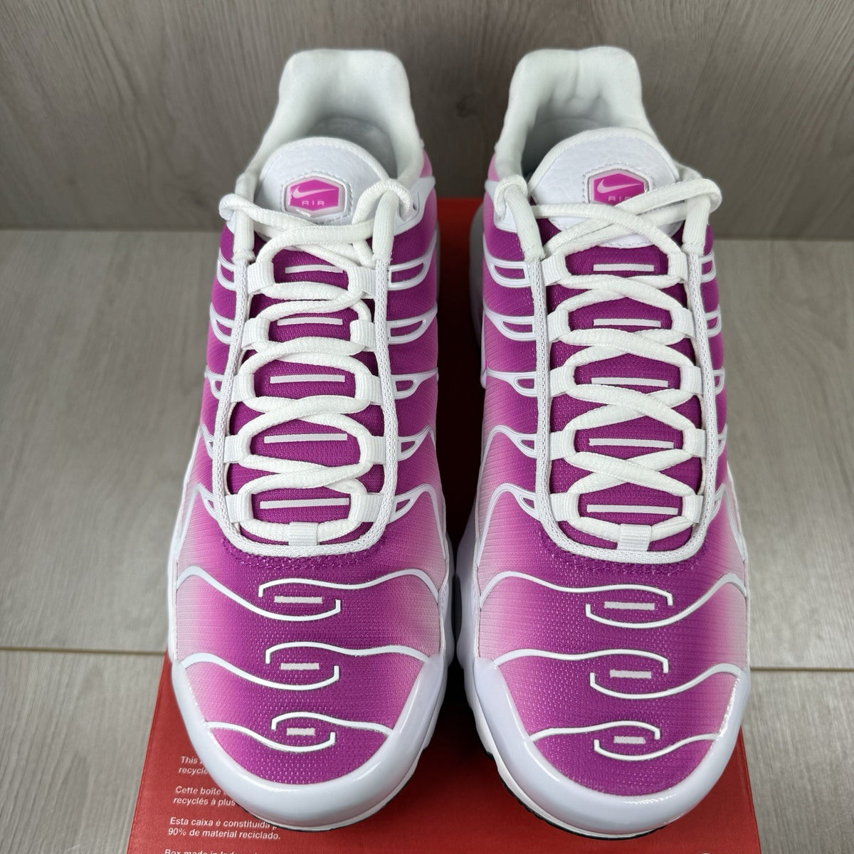 Nike Air Max Plus TN white trainers with fire pink foam fade and logo detailing.