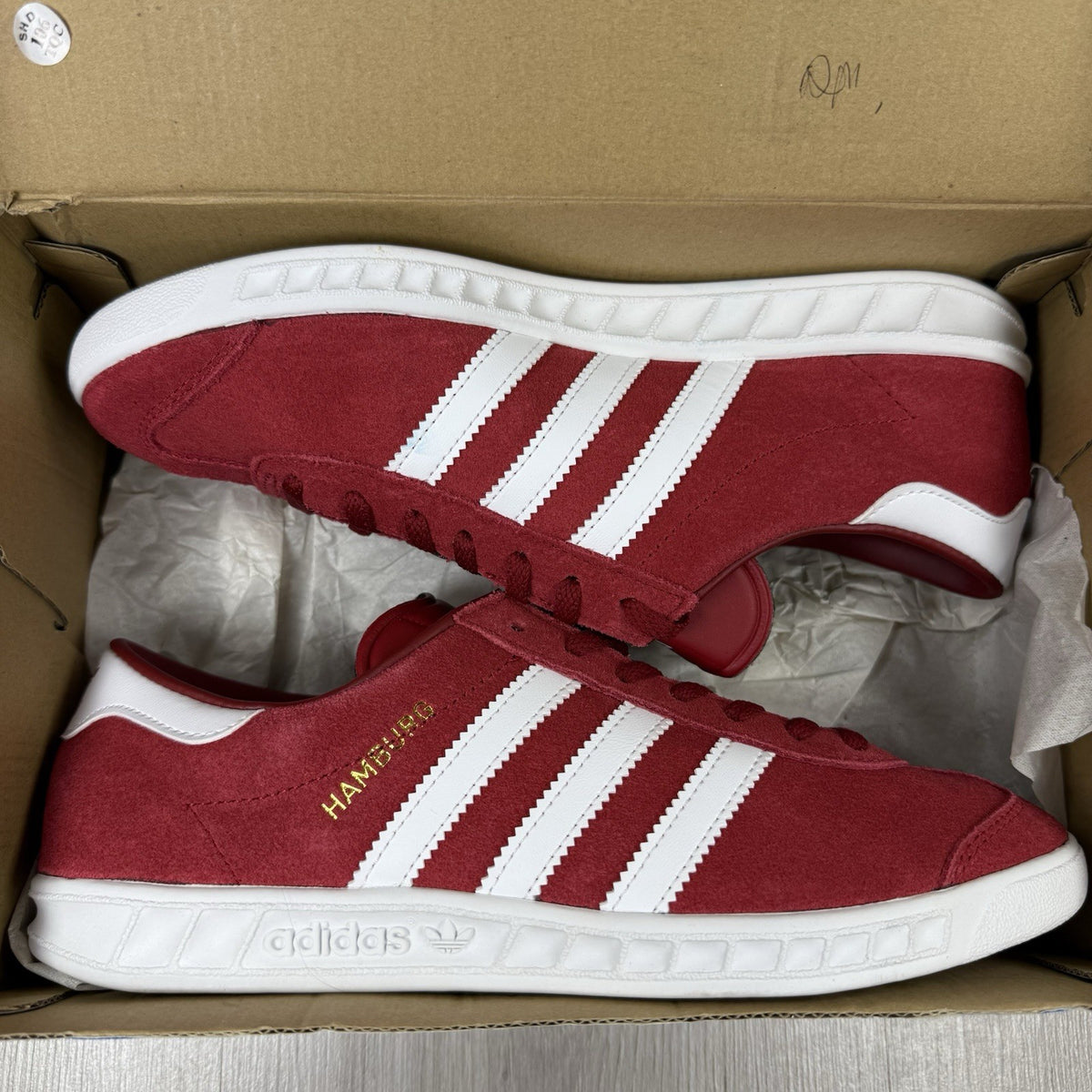 Adidas red trainers with white stripes and logo, classic suede material.