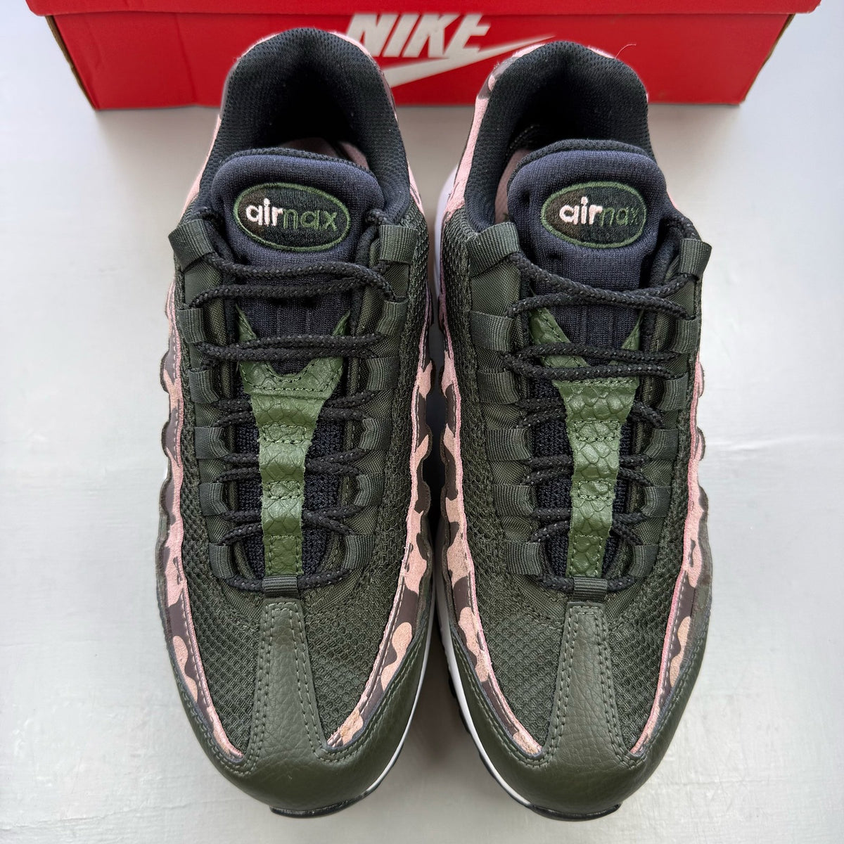 Nike black trainers with pink camo accents and white sole, featuring logo details.
