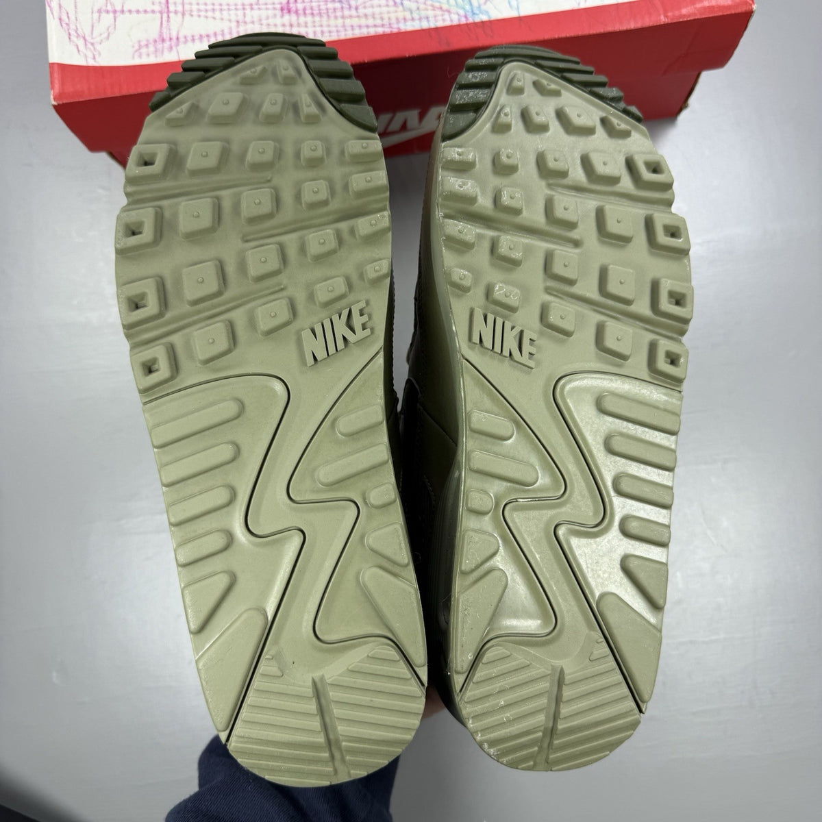 Nike Air Max 90 Essential green trainers with khaki accents and signature swoosh logo.