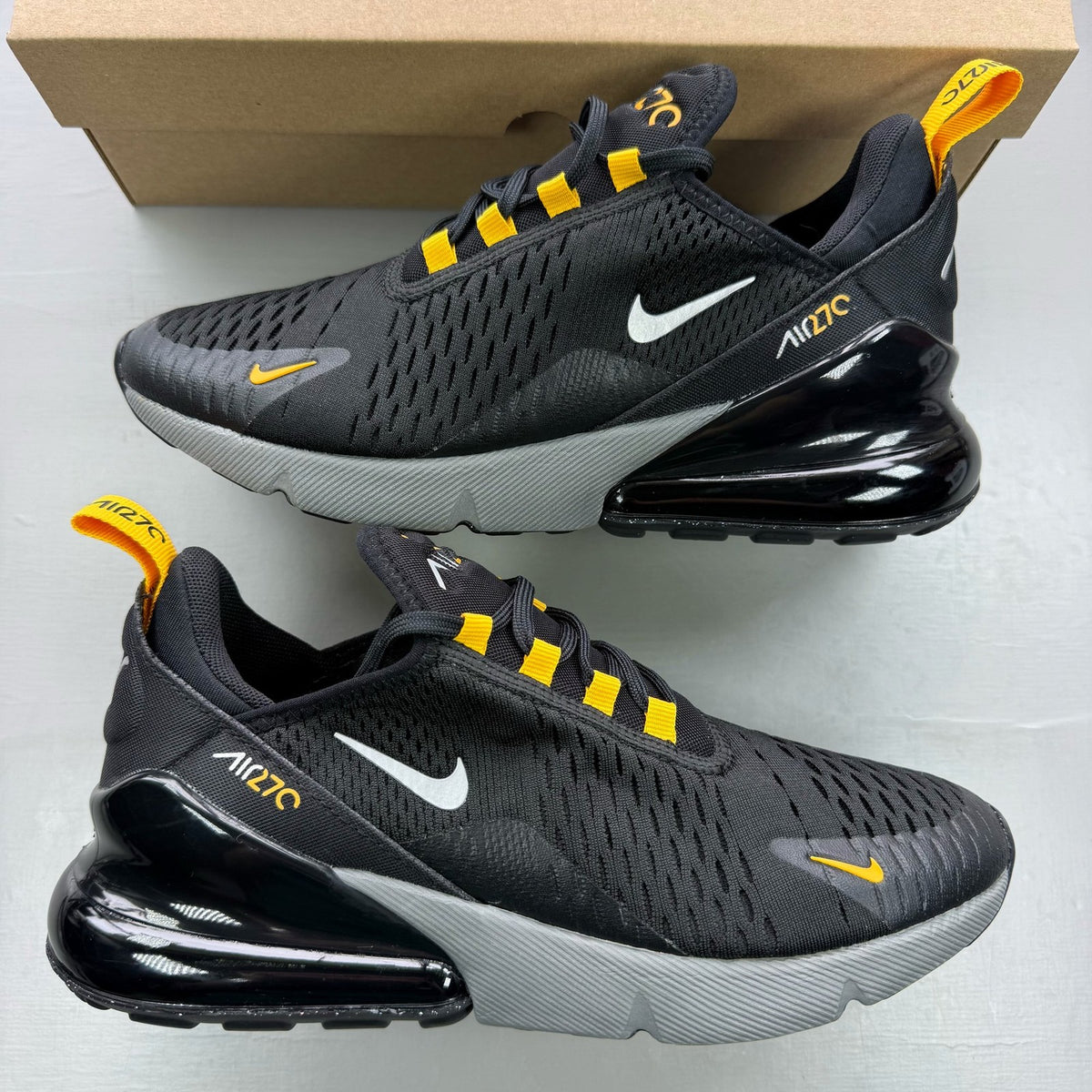 Nike black Air Max 270 trainers with grey and university gold accents, logo on tongue.