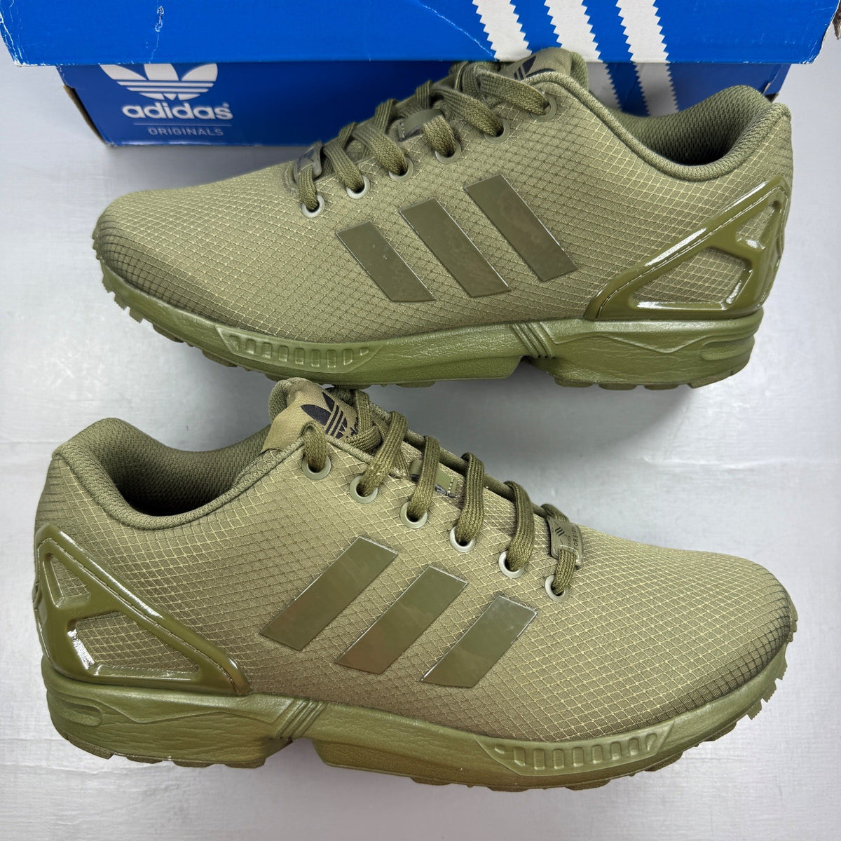 Adidas green ZX Flux trainers with distinctive logo and sleek running design.
