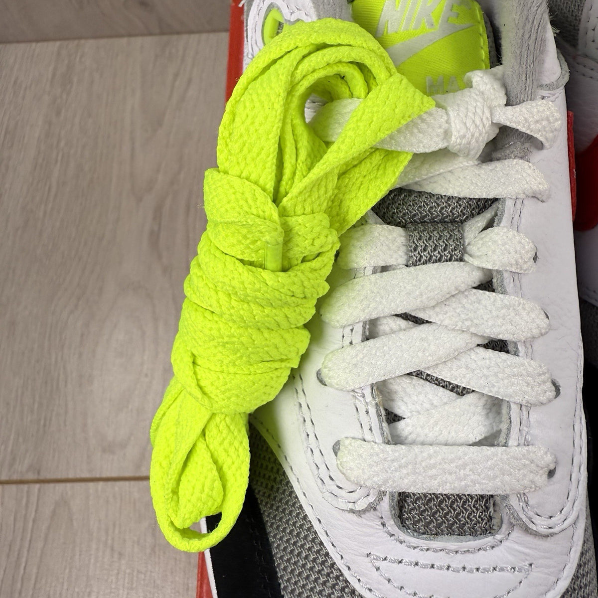 Nike Air Max 1 trainers white with chili volt accents and black detailing.