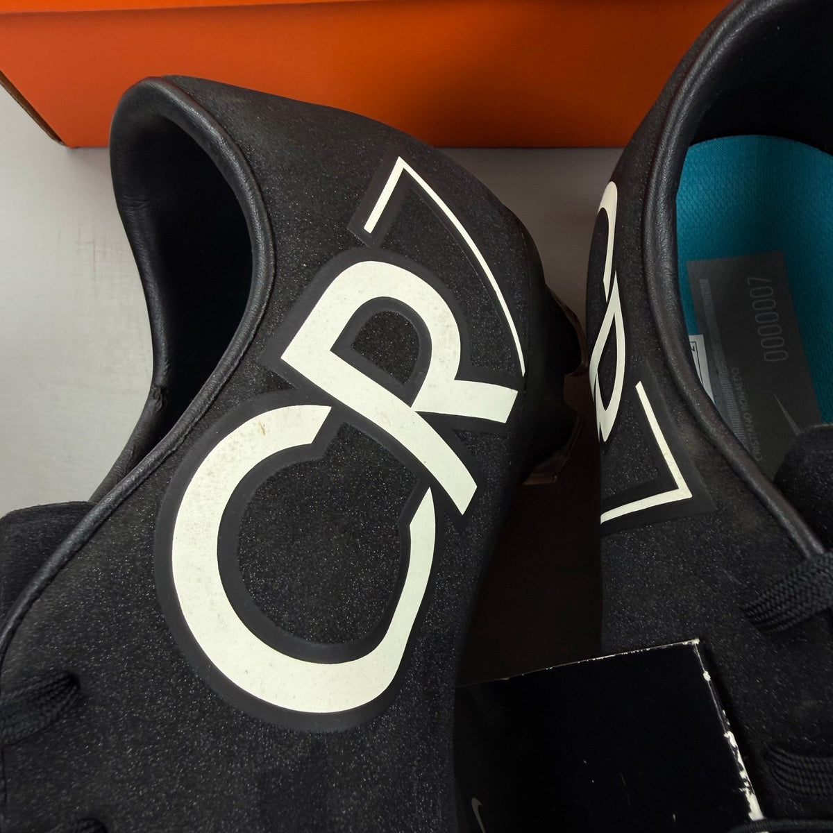 Nike black football boots with white Mercurial logo, sleek design, synthetic material.