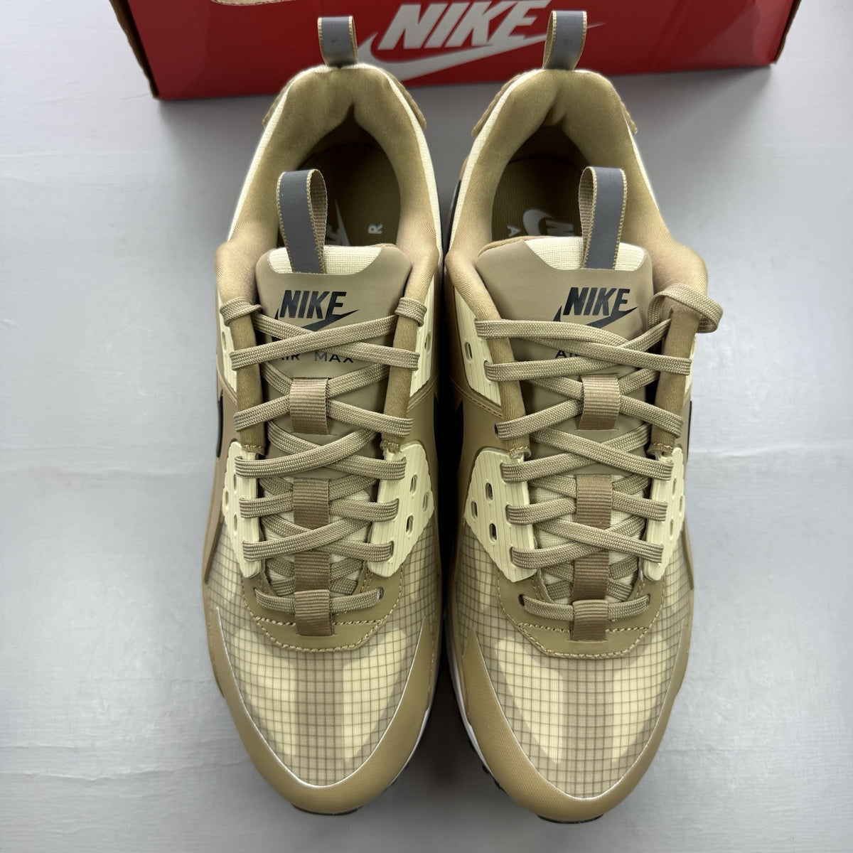 Nike Air Max 90 Drift beige trainers with black and white accents, featuring logo details.