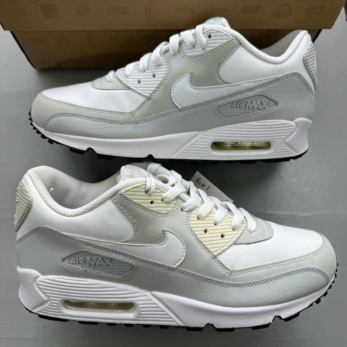 Nike Air Max 90 white trainers with grey accents and logo detailing.