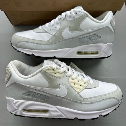 Nike Air Max 90 white trainers with grey accents and logo detailing.