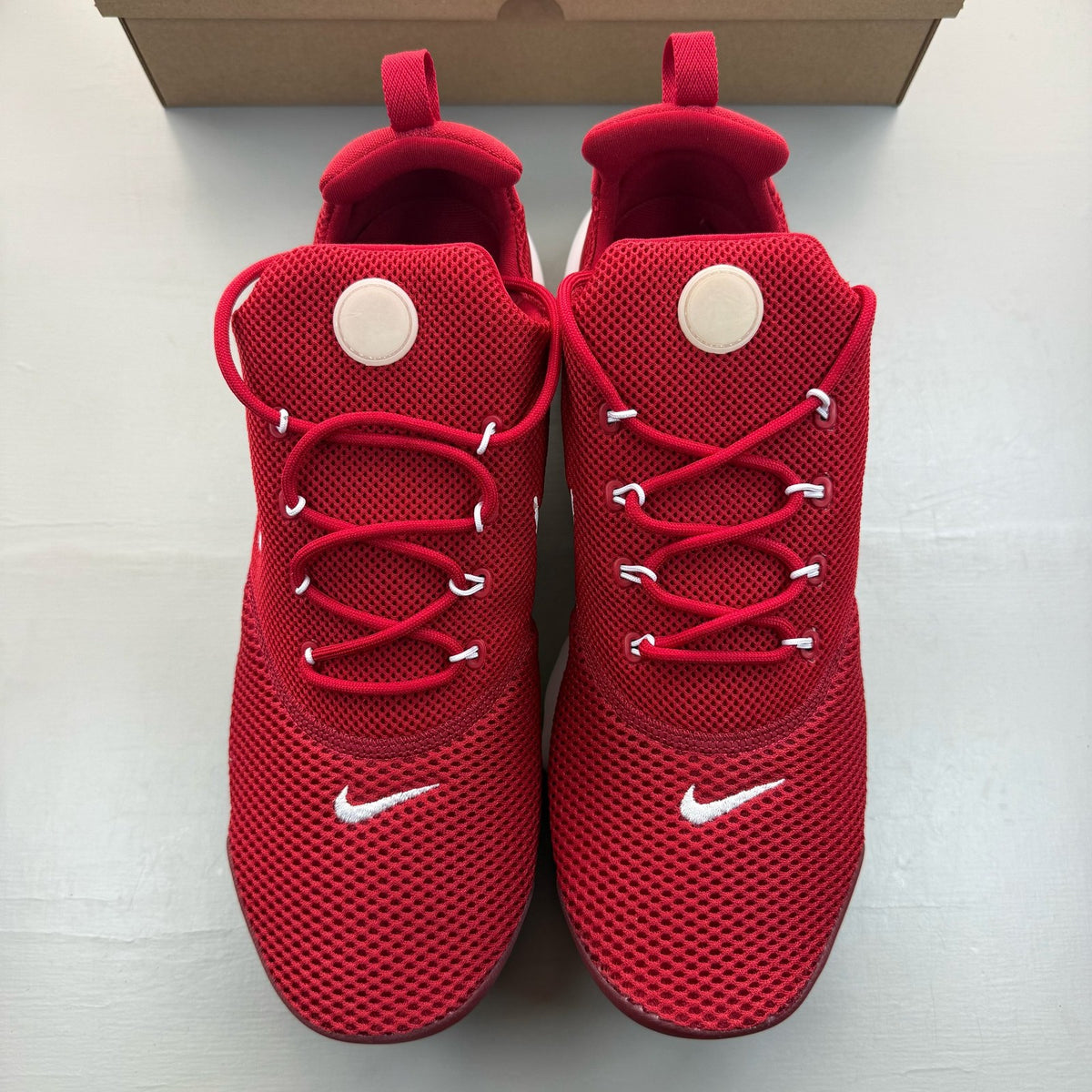 Nike Presto Fly red trainers with white accents and logo detail.