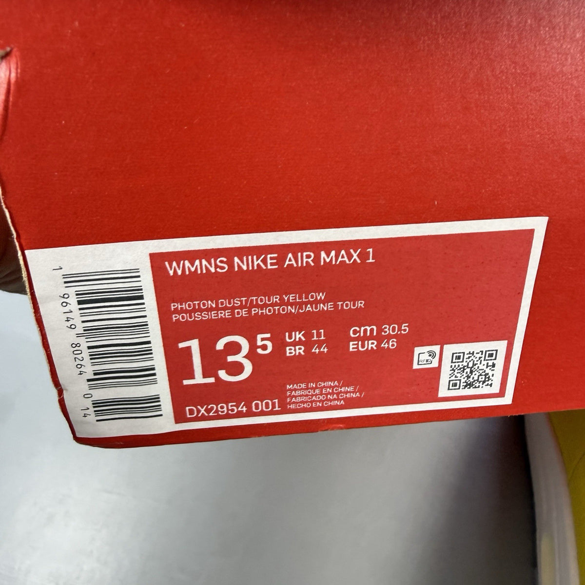 Nike Air Max 1 white trainers with yellow accents and grey detailing.