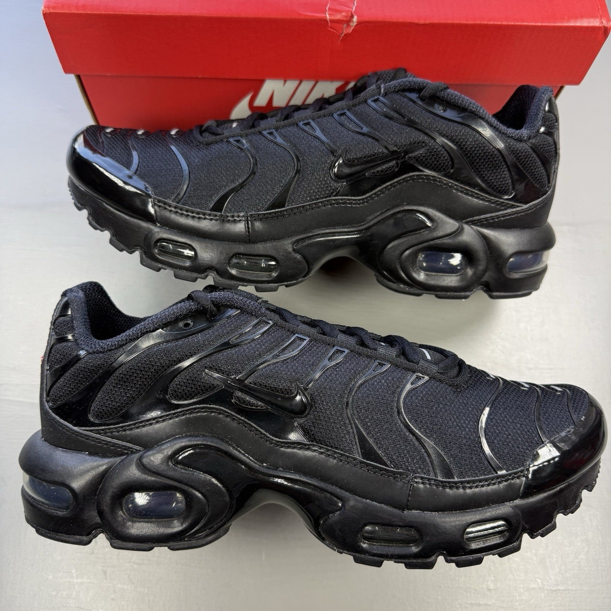 Nike Air Max Plus TN black trainers featuring distinctive wavy design and cushioned sole.