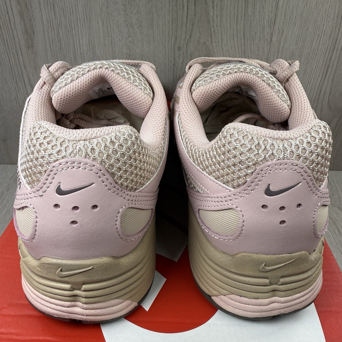 Nike beige trainers with pink accents and mesh detailing, featuring iconic swoosh logo.