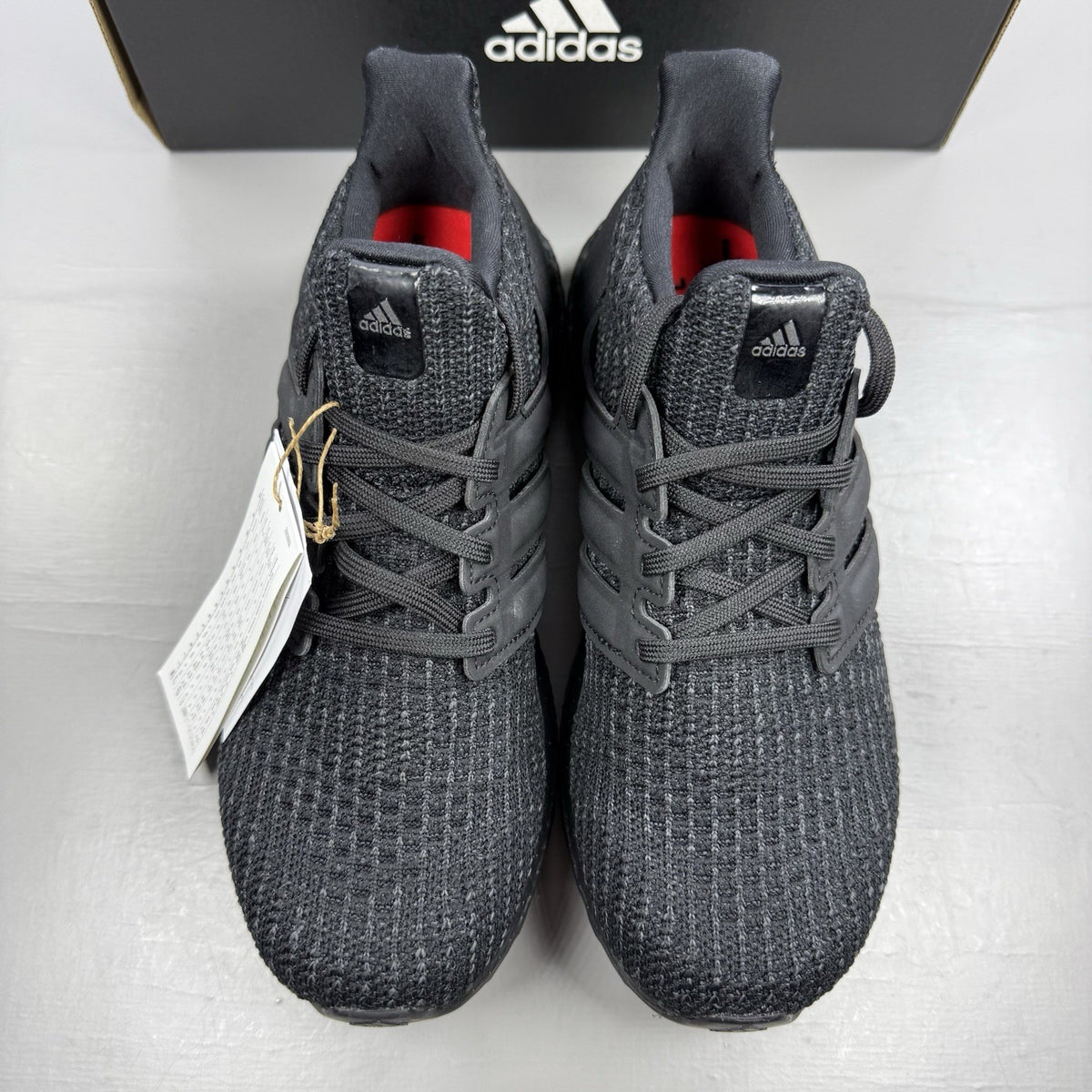 Adidas black trainers with grey accents and signature three-stripe logo.