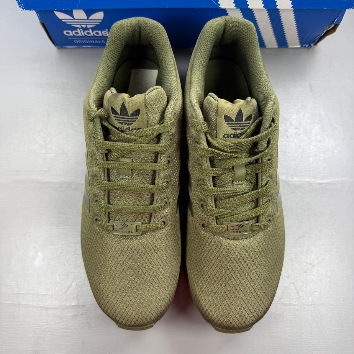 Adidas green ZX Flux trainers with distinctive logo and sleek running design.