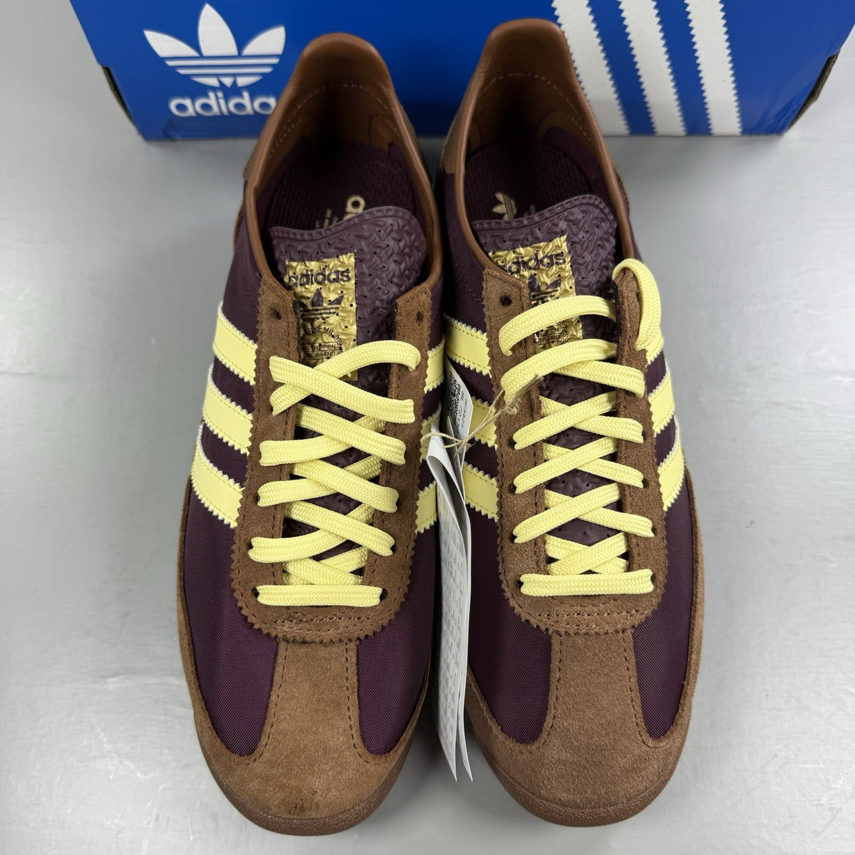 Adidas brown trainers with retro design and classic logo detail.