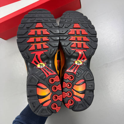 Nike black Air Max Plus TN trainers with red and orange accents and signature logo.