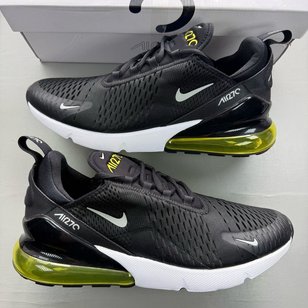 Nike black trainers with Opti Yellow accents and Air Max cushioning.