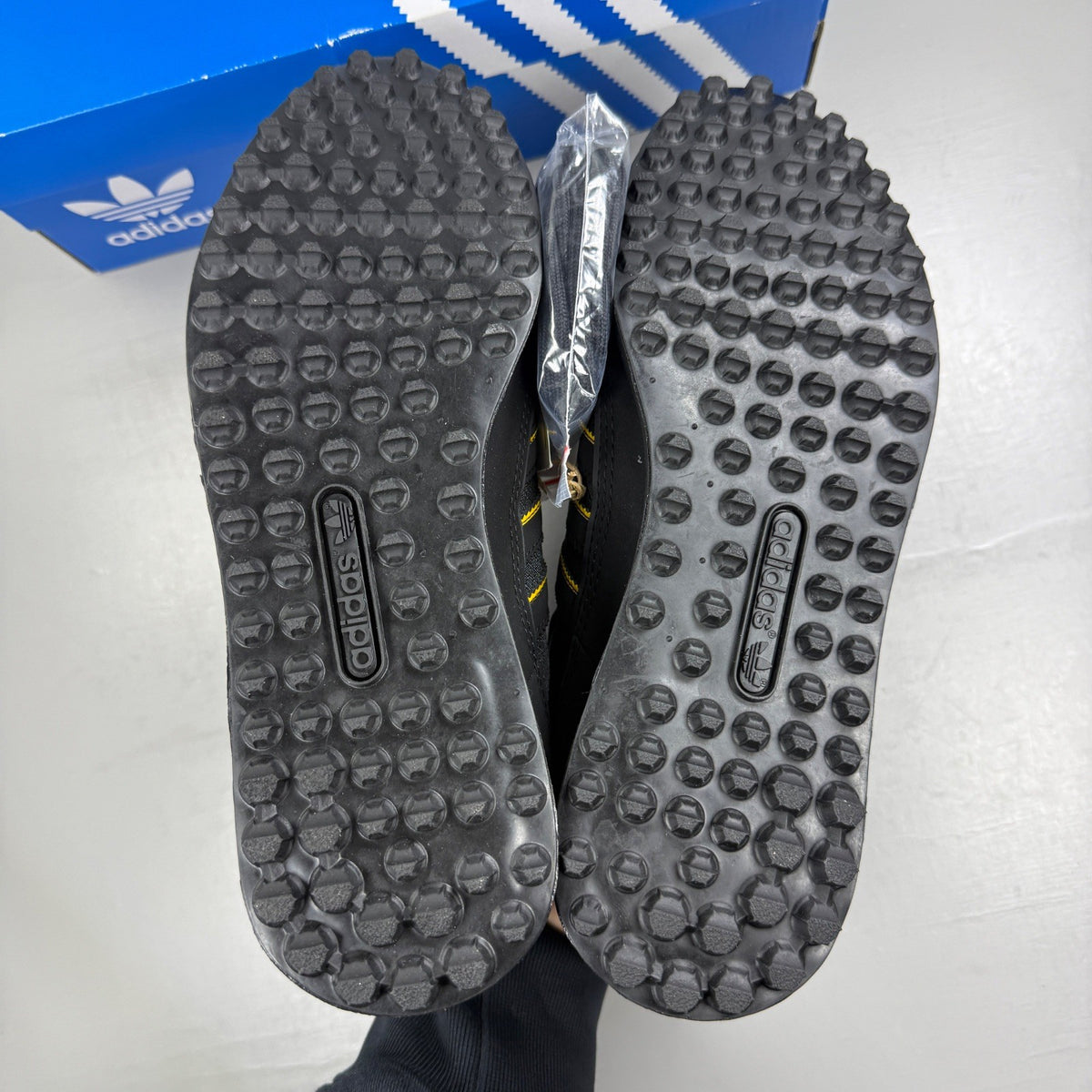 Adidas black deck shoes with gold accents and classic three-stripe logo.
