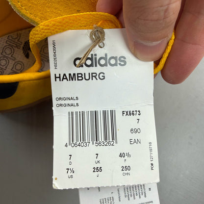 Adidas yellow trainers with black and gold accents, featuring iconic logo detail.
