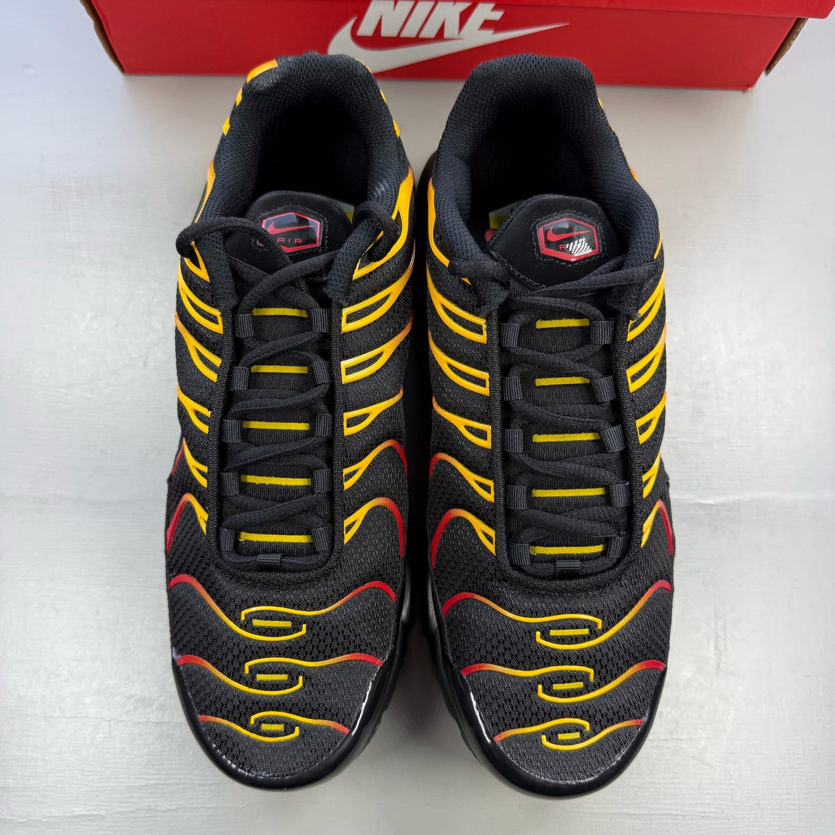 Nike Air Max Plus TN black with university gold and red accents, featuring iconic logo.