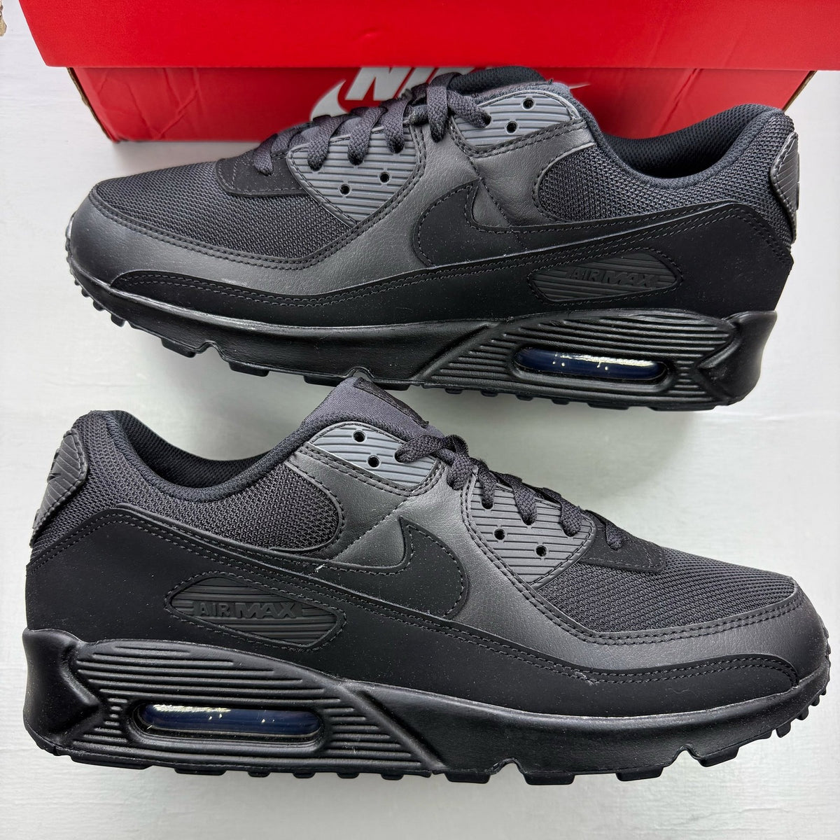 Nike Air Max 90 trainers black with logo detailing and sleek design.