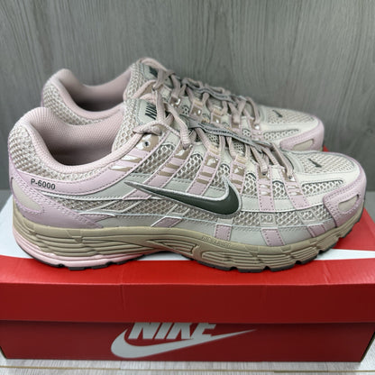 Nike beige trainers with pink accents and mesh detailing, featuring iconic swoosh logo.