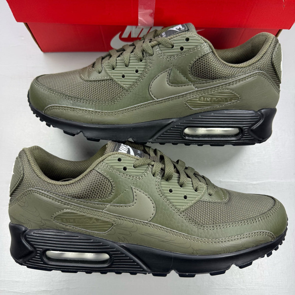 Nike Air Max 90 olive green trainers with reflective detailing and black accents.