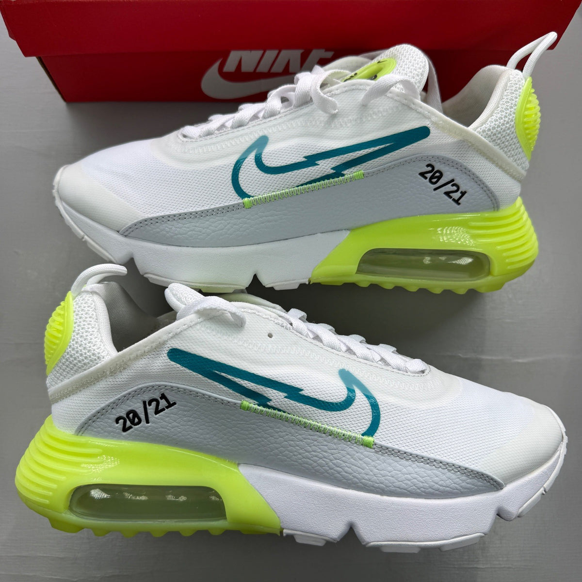 Nike white trainers with aquamarine and lime glow accents, featuring iconic logo details.