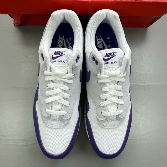 Nike Air Max 1 white trainers with purple accents and logo detail.