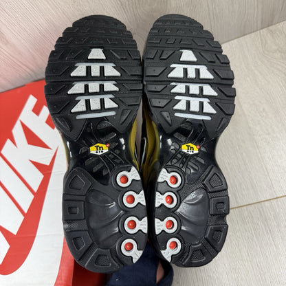 Nike Air Max Plus TN trainers black with gold accents and distinctive wavy pattern.