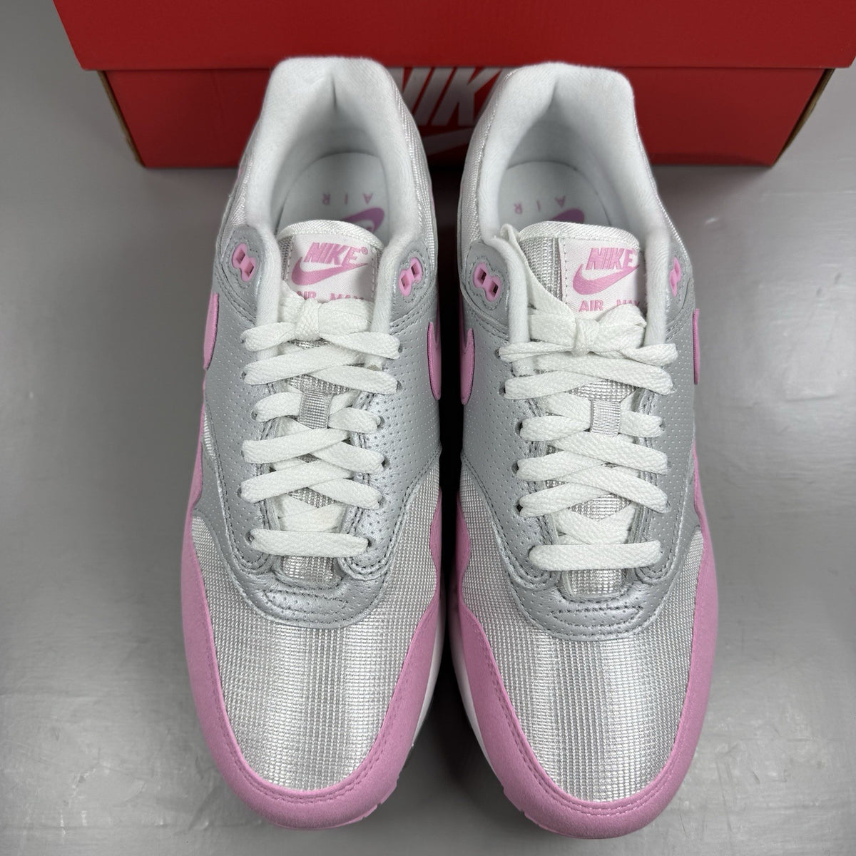 Nike Air Max 1 trainers pink with metallic accents and classic logo detailing.