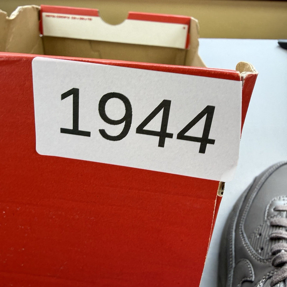 Nike Air Max 90 trainers grey with red accents and logo detail.