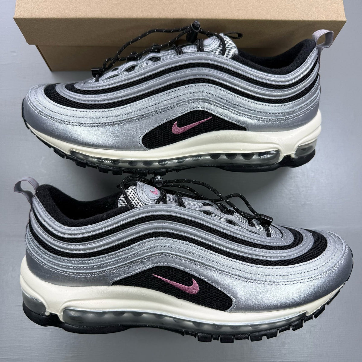 Nike Air Max 97 metallic silver trainers with berry accents and signature swoosh logo.