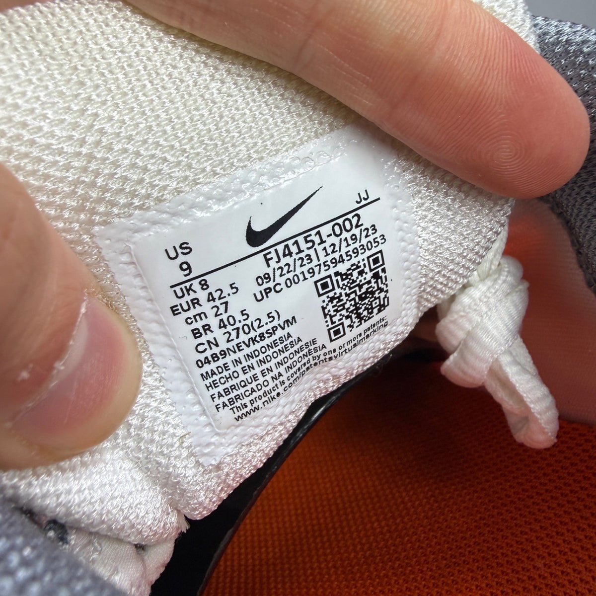 Nike running shoes orange with grey accents and distinctive logo detailing.