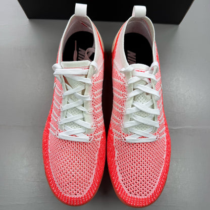 Nike Air VaporMax 2 Flyknit white trainers with hot punch red accents and breathable material.