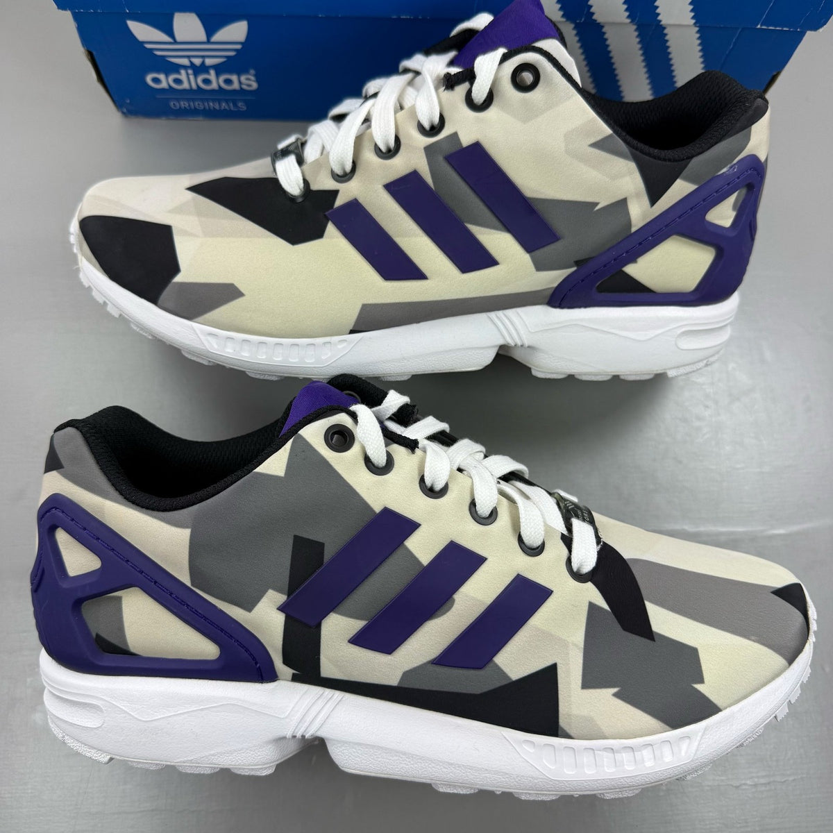 Adidas ZX Flux white trainers with purple and black accents, featuring iconic three-stripe logo.