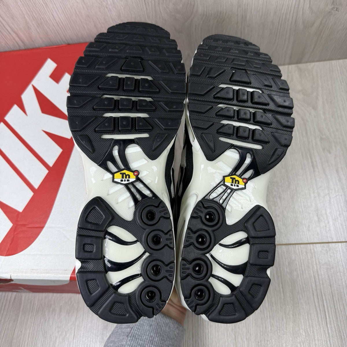 Nike Air Max Plus TN ESS trainers white with black accents and signature swoosh logo.